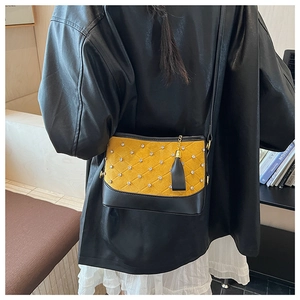 Detail of yellow quilted suede shoulder bag with rhinestones and black leather tassel