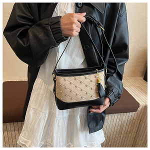 Quilted apricot suede bucket bag with crystal studs and black tassels on a model