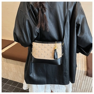 Detail of quilted beige fabric with rhinestones and black leather bucket bag base