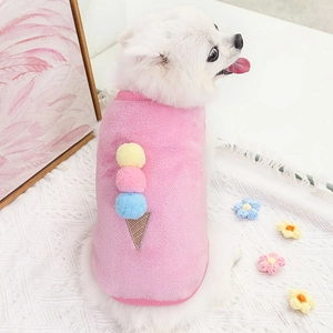 Dettaglio del gilet di peluche rosa per animali con pompon colorati indossato da un cane
