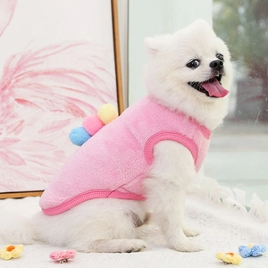 Dettaglio del gilet in pile rosa per animali con pompon indossato da un cane bianco