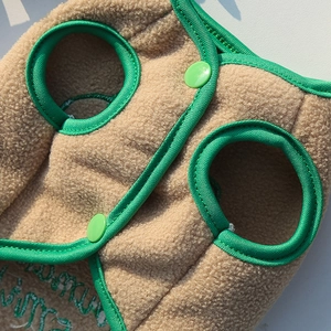 Close-up of beige fleece pet vest showing green resin buttons and soft Sherpa texture