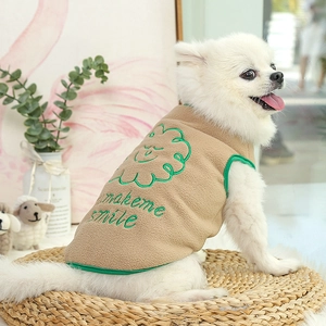 Detail of warm khaki fleece vest with green smile embroidery on a small white dog
