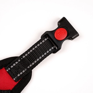 Detail of dog harness safety buckle with red locking switch and reflective nylon strap