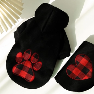 Detail of black pet hoodie showing red plaid paw print embroidery and soft winter fabric