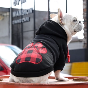 Detail view of black pet hoodie featuring a red plaid paw patch on a white bulldog
