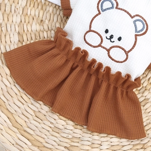 Détail du tissu gaufré et broderie d'ours sur une robe pour animaux de compagnie