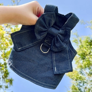 Detail of dark blue denim dog harness featuring a large bow and silver D-ring