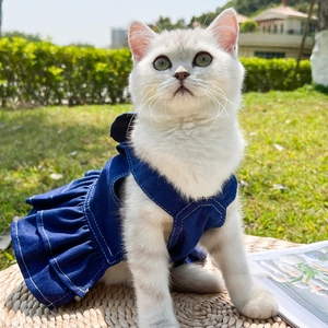 Detail of dark blue denim pet dress with pleated hem and white stitching on a cat