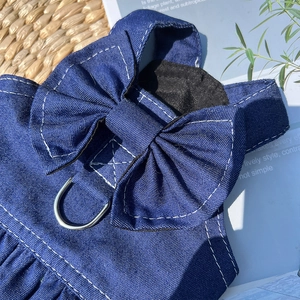 Detail of dark blue denim pet dress with stitching, bow, and metal D-ring for leash attachment