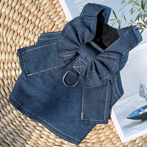Detail of denim dog harness with large bow and metal D-ring on woven texture mat