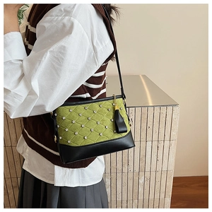 Close-up of green quilted shoulder bag with sparkling rhinestones and black leather tassel