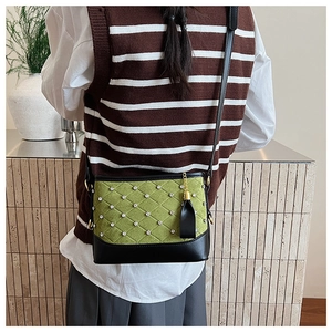 Detail of green quilted suede bag with diamond studs and black leather fringe charm