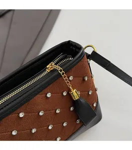 Detail of brown suede shoulder bag featuring rhinestone quilting and gold tassel zipper