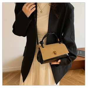 Detail of a vintage-style crossbody bag with khaki suede flap and golden twist lock