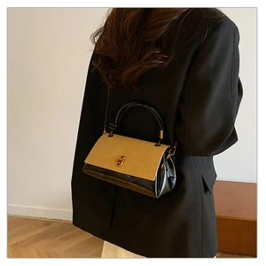 Detail of a vintage contrast flap bag with golden twist-lock and black leather handle