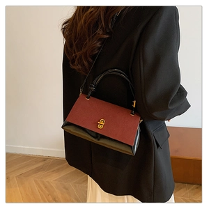 Detail of burgundy suede and black patent leather patchwork bag with gold metal lock