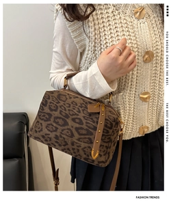 Sac Boston imprimé léopard en daim avec détails dorés porté par un mannequin