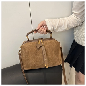 Détail du sac polochon en daim marron avec anneaux métalliques dorés et double fermeture