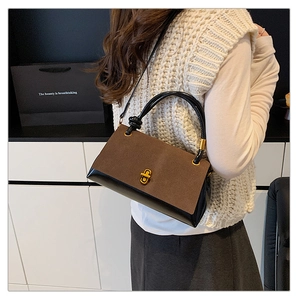 Detail of suede patchwork handbag with golden twist lock and black braided knot handle
