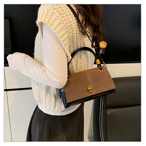 Detail of suede patchwork handbag featuring a golden twist lock and brown matte texture