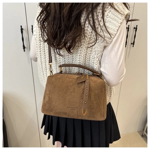 Vue détaillée d'un sac oreiller en daim marron porté par un mannequin en intérieur sobre