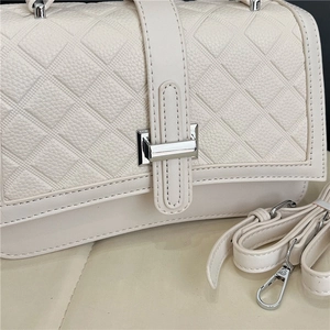 Close-up of quilted beige handbag showing lychee texture and silver metal clasp