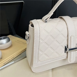 Detail of cream quilted texture and silver metal clasp on minimalist shoulder bag