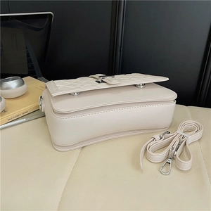 Detailed close-up of cream quilted PU leather bag with silver rectangular metal lock
