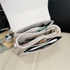 Detailed interior of a beige crossbody bag with multi-compartment accordion structure