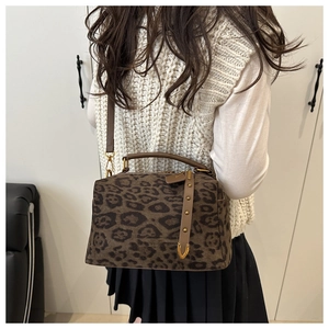 Détail du sac à main léopard en daim avec poignée en cuir marron et accessoires en métal