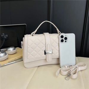 Quilted crossbody bag detail with metal buckle and smartphone for size scale