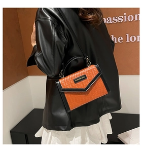 Détails de la texture tissée orange et des coutures en cuir noir sur ce sac à bandoulière