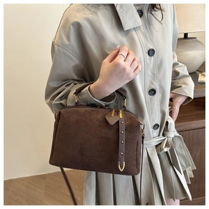 Détail du sac Boston en daim café avec poignées en cuir vintage et ferrures dorées