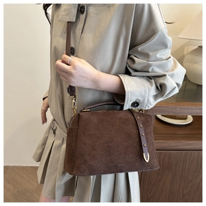 Détails du sac bandoulière en daim marron avec rivets dorés et poignées en cuir