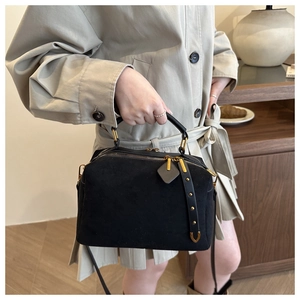 Détail du sac polochon en daim noir avec ferrures dorées et pampilles à rivets chic
