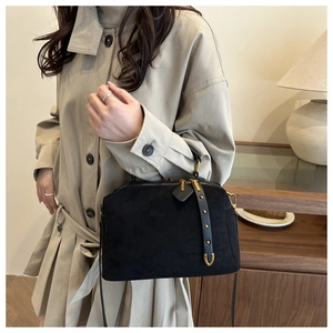 Détail du sac polochon en daim noir avec rivets dorés vintage et accents métalliques