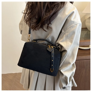 Détail du sac polochon en daim noir avec fermeture éclair dorée et pendentif à clous