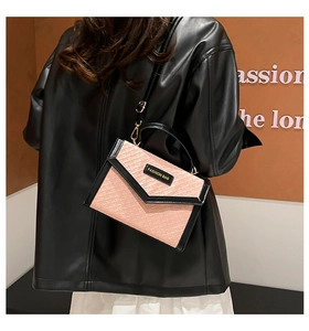 Detailed view of pink woven texture flap bag with black strap on leather jacket