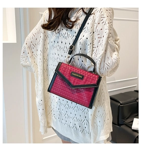 Close-up of woven rose red crossbody bag with gold fashion plate and black strap