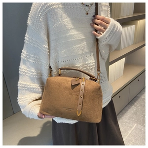 Détail du sac docteur vintage en daim marron avec rivets en bronze et bandoulière en cuir