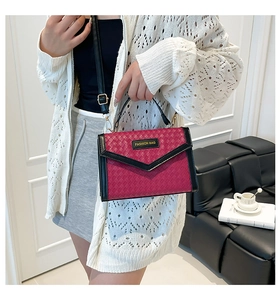 Detail of fuchsia woven envelope bag with black leather trim and metal fashion logo