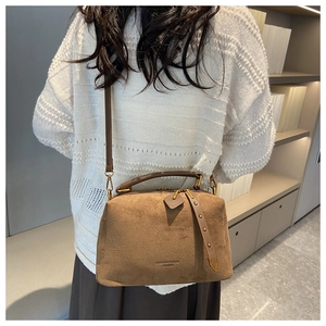 Vue détaillée de la texture du sac oreiller en daim marron et poignée métal