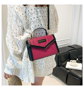 Close-up of fuchsia woven handbag with black leather trim and metal logo detail