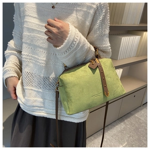 Détail d'un sac oreiller en daim vert avec lanières en cuir marron et rivets dorés