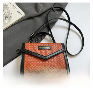 Detail view of woven orange leather handbag with black trim and Fashion Bag emblem