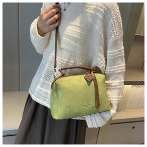 Détail du sac Boston en suédine verte avec texture mate et poignées en cuir marron