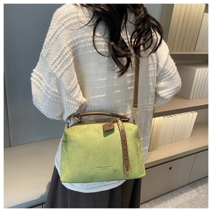 Détail du sac polochon en daim vert clair avec lanières brunes et rivets dorés