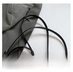 Detailed close-up of woven brown leather texture and black glossy adjustable shoulder strap