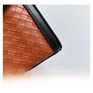 Macro shot of the intricate orange leather weave and black stitched trim detail on the bag